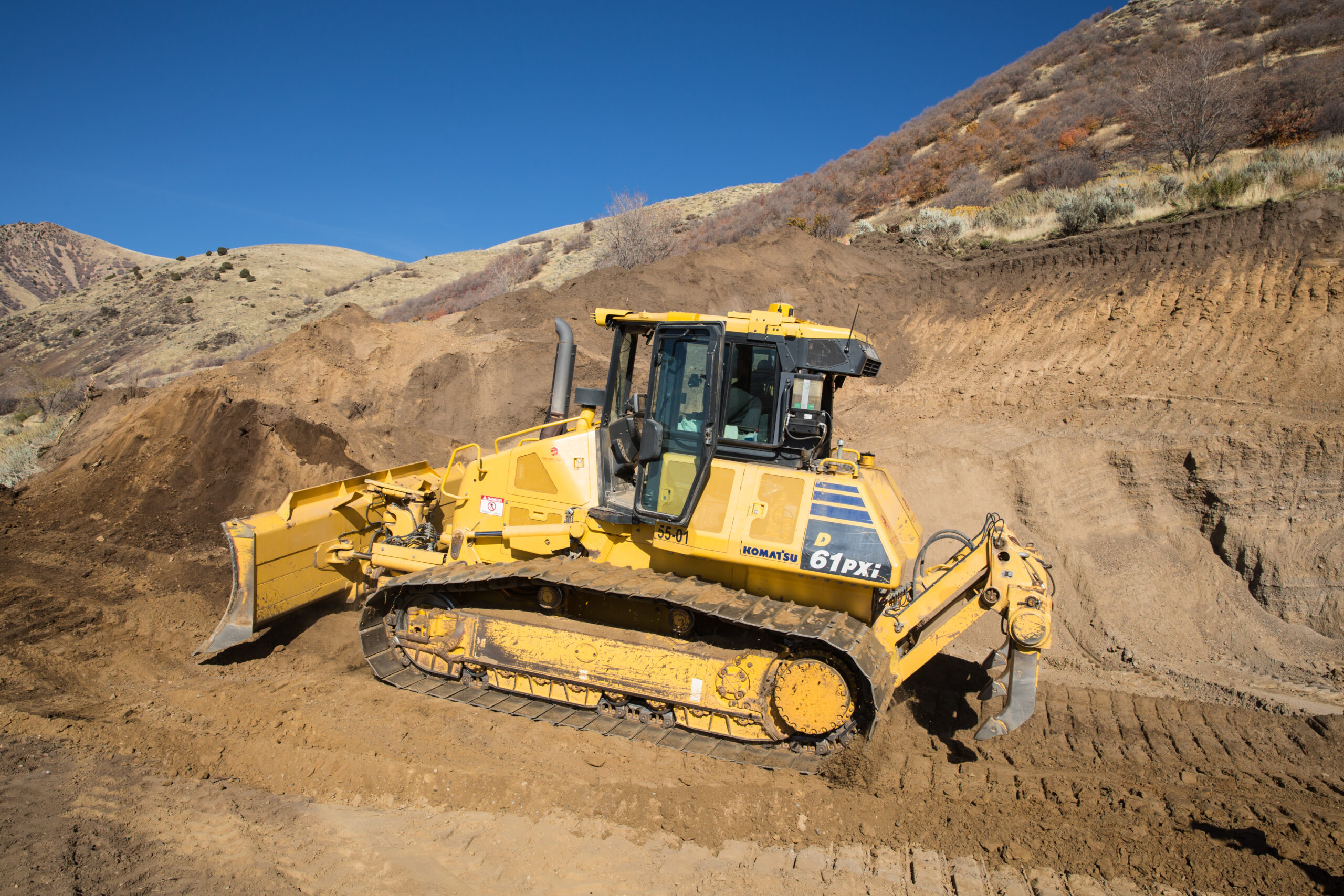 Komatsu D61PXi bulldozer moving soil on a hillside construction site, symbolizing the importance of ROI tracking in construction marketing.