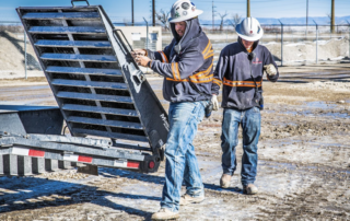 Construction workers unloading equipment at an active job site, demonstrating hands-on project execution and skilled labor.